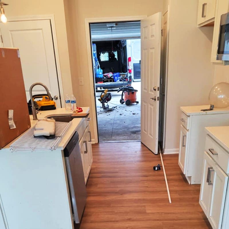 Warm-toned vinyl plank flooring running into a kitchen